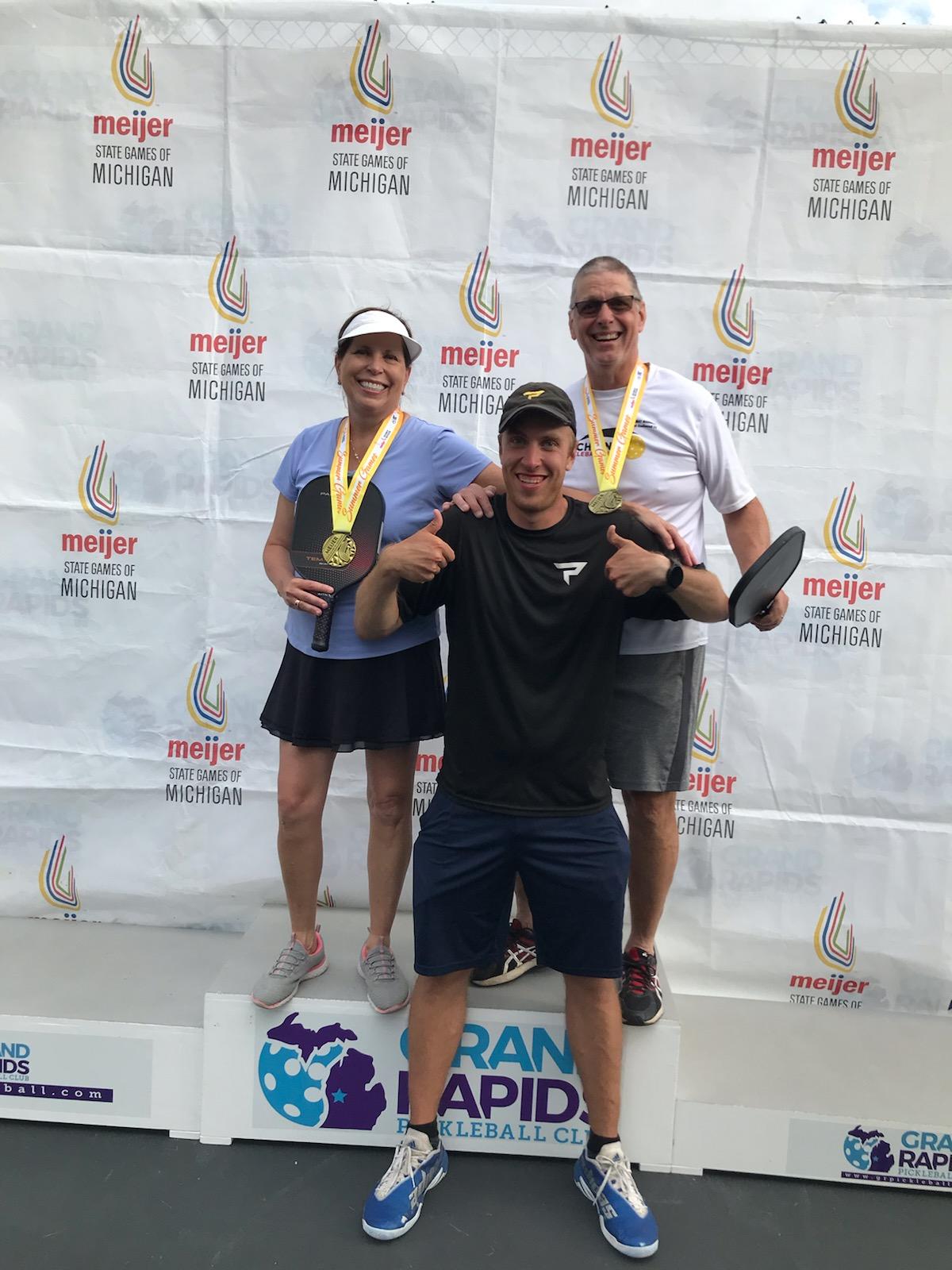 Becky Afman, Jaron, and a teammate celebrating State Games of Michigan medals